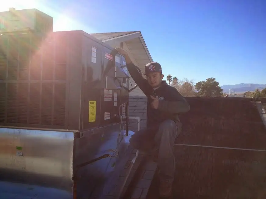 HVAC technician performing Air Duct Cleaning on a rooftop unit in Porterville